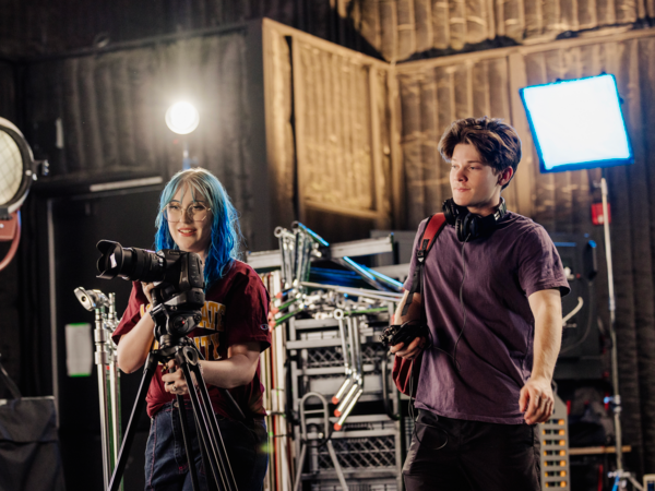 Two students operating equipment on set.